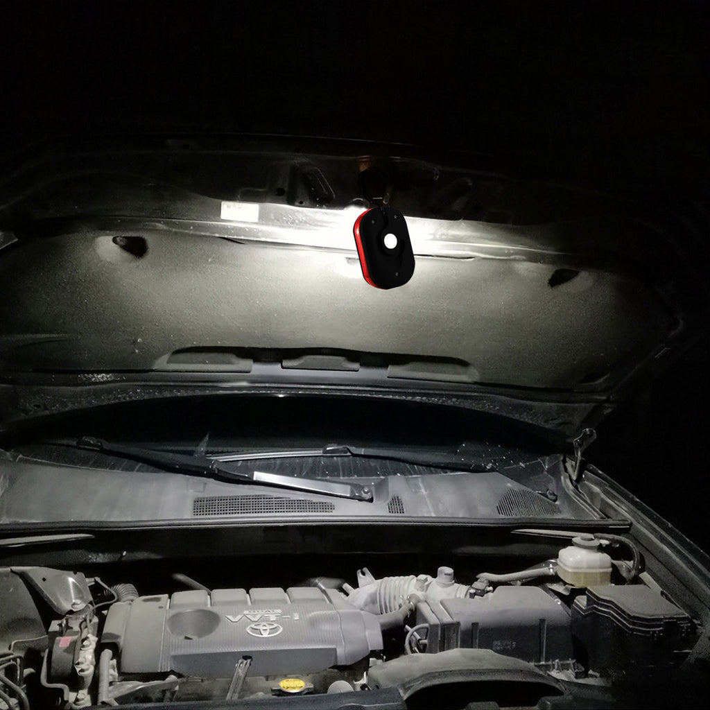 LED work light hanging under a car hood at night